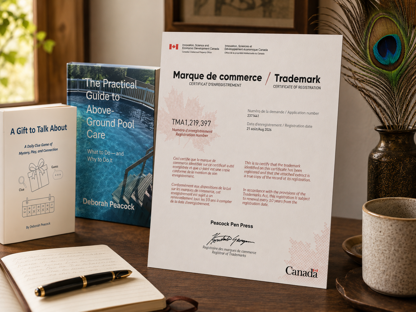 Peacock Pen Press trademark registration certificate displayed on a desk beside a peacock feather and writing materials